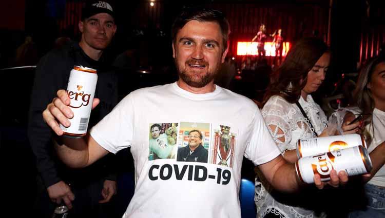 Fans Liverpool merayakan kemenangan di luar Anfield dengan kaos bertuliskan COVID-19.