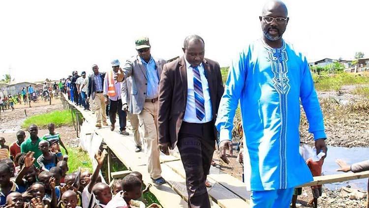 Fofee Kamara (menggunakan jas dan berdasi) ketika mengawal legenda AC Milan yang juga Presiden Liberia, George Weah.