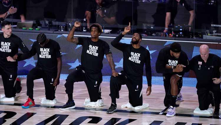 Para pemain berlutut dan mengenakan kaus Black Lives Matter selama lagu kebangsaan diputar sebelum laga NBA Brooklyn Nets vs Orlando Magic di ESPN Wide World Of Sports Complex, Sabtu (01/08/20).