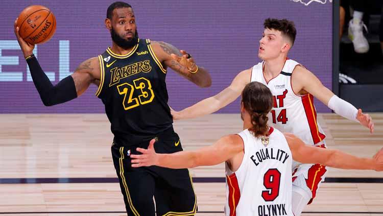 Dua pemain Miami Heat menempel ketat LeBron James yang hendak mengoper bola ke rekan-rekannya di LA Lakers.