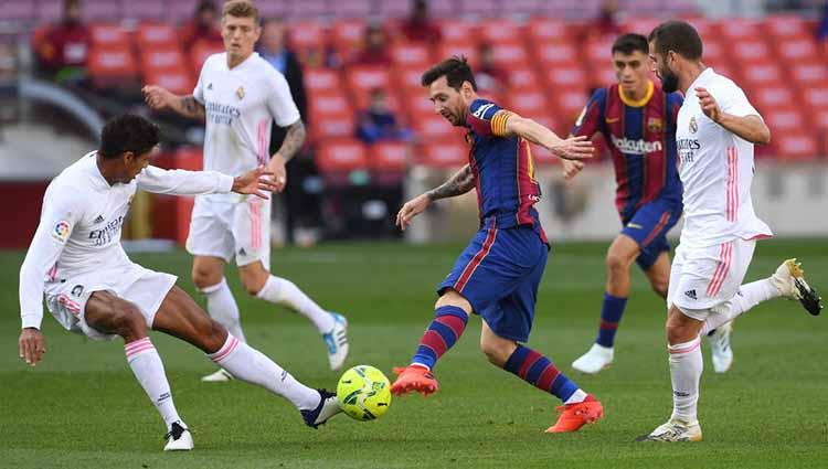 Lionel Messi saat mengontrol bola dan dihadang Raphael Varane dan Luka Modric dalam pertandingan antara FC Barcelona dan Real Madrid di Camp Nou, Sabtu (24/10/2020). - INDOSPORT