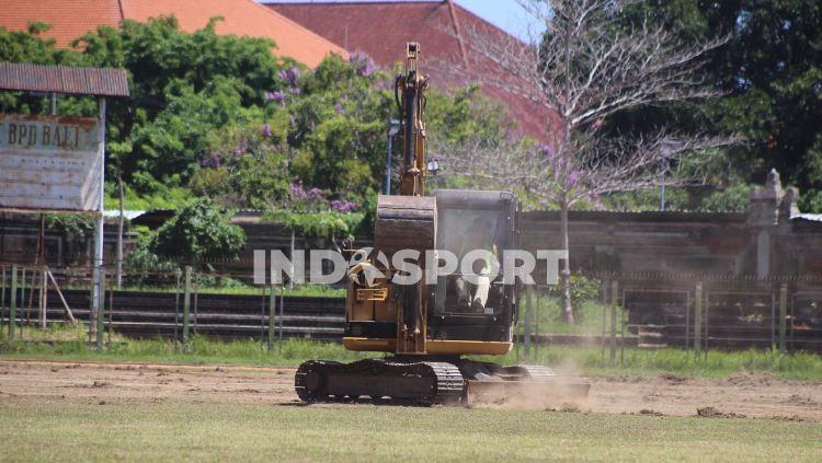 Seorang pekerja saat mengoperasikan buldozer untuk mengeruk lapangan di Stadion Ngurah Rai, Denpasar. - INDOSPORT