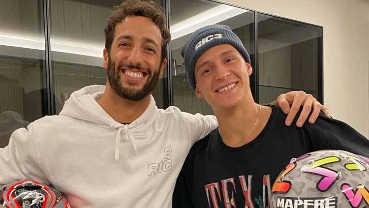 Pembalap Formula 1 asal Australia, Daniel Ricciardo (kiri), bertukar helm dengan pembalap MotoGP asal Prancis, Fabio Quartararo. - INDOSPORT