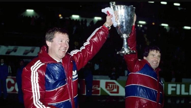 Sir Alex Ferguson mengangkat trofi Piala Super Eropa saat menangani Aberdeen, 20 Desember 1983. - INDOSPORT