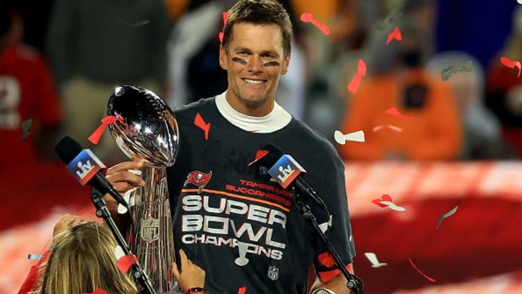Tom Brady memegang trofi juara Superbowl.