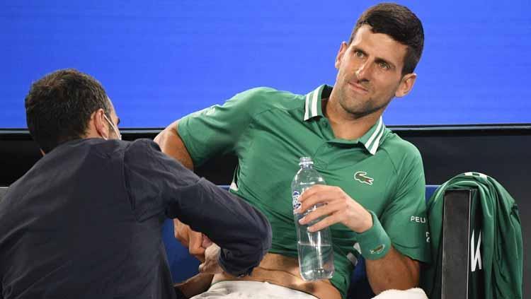 Novak Djokovic menerima perawatan di tengah pertandingan babak ketiga Australian Open 2021. - INDOSPORT