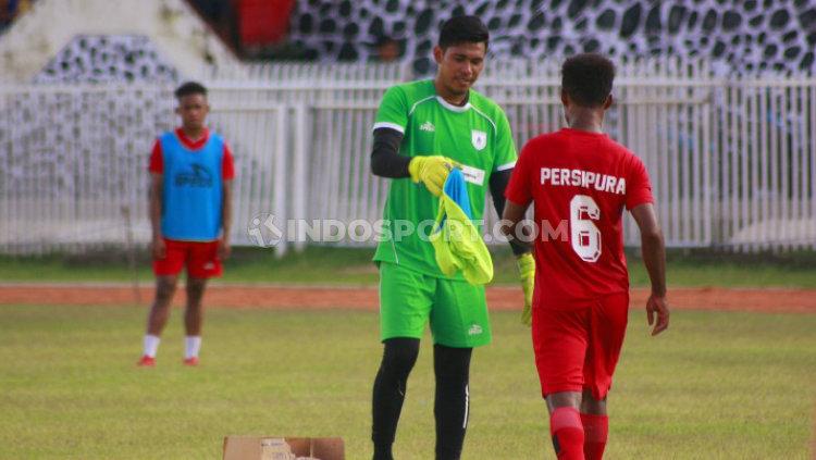 Kiper Persipura Jayapura, Dede Sulaiman saat memberikan rompi latihan kepada rekannya.