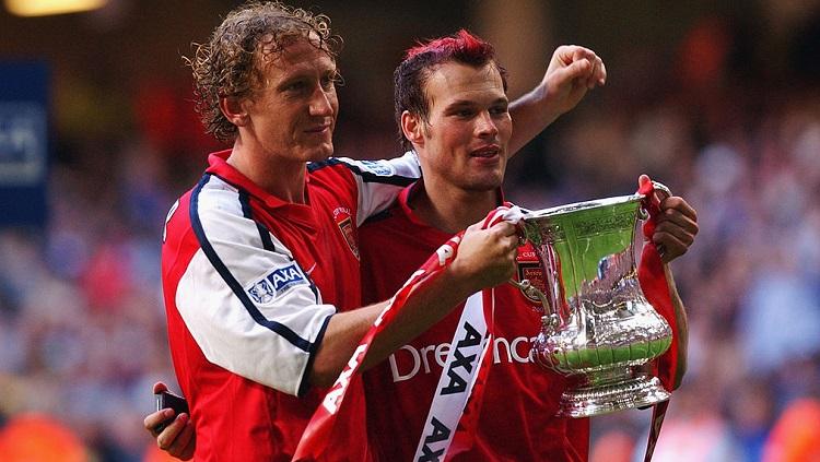 Pose Ray Parlour dan Freddie Ljungberg memegang trofi Piala FA usai mengalahkan Chelsea di final, 4 Mei 2002. - INDOSPORT