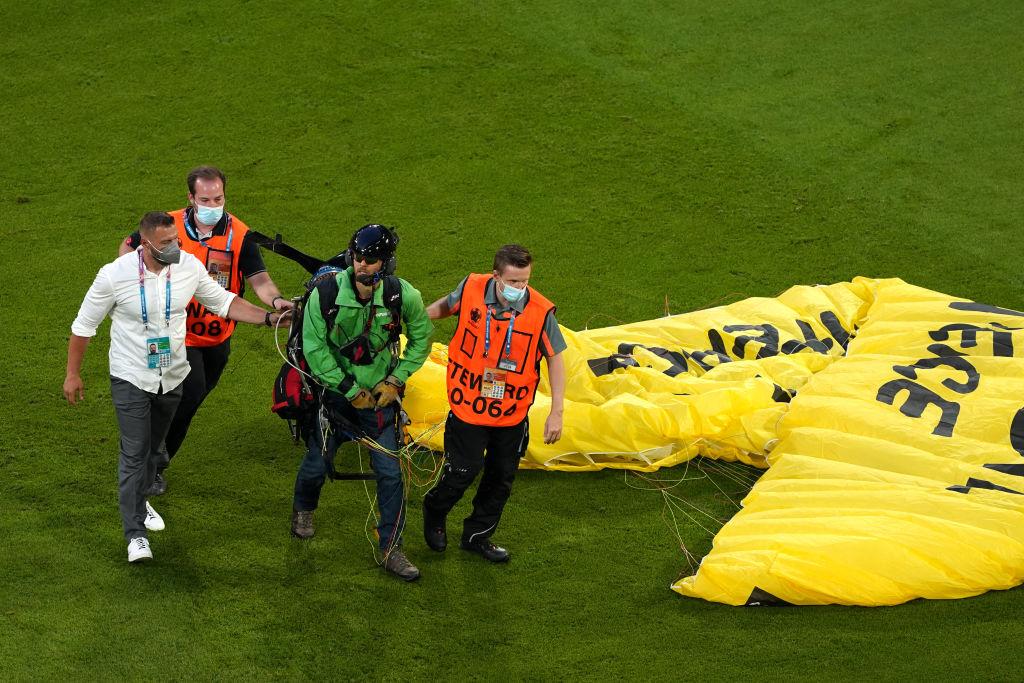 Seorang penerjun payung membuat sensasi di laga Euro 2020 antara Prancis vs Jerman dan berhasil diamankan oleh petugas keamanan, Rabu (16/6/21) dini hari WIB.