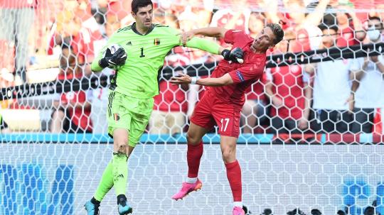 Kiper Belgia, Thibaut Courtois (kiri), beradu dengan pemain Denmark, Stryger Larsen, pada laga Grup B Euro 2020, Jumat (17/06/21) dini hari WIB.