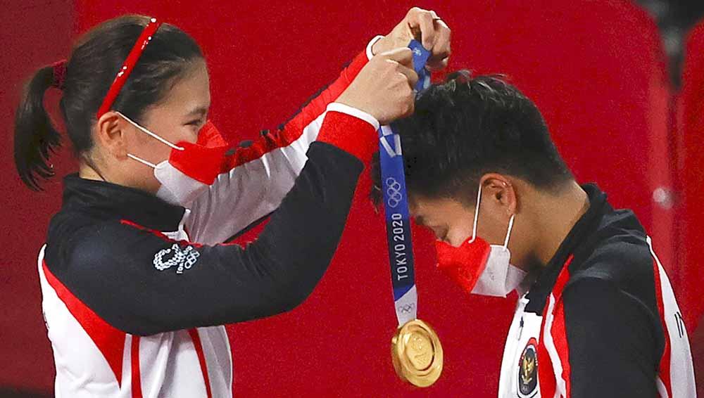 Peraih medali emas Greysia Polii dari Indonesia menempatkan medali pada rekan setimnya Apriyani Rahayu di Olimpiade Tokyo 2020.