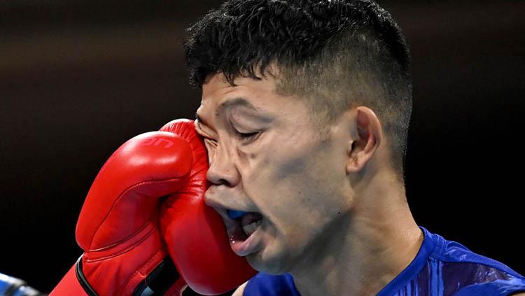 Ryomei Tanaka (Jepang, seragam biru) menerima pukulan hook kiri Yuberjen Rivas (Kolombia) di perempat final tinju 48-52 kg Olimpiade Tokyo 2020. Copyright: Luis Robayo - Pool/Getty Images