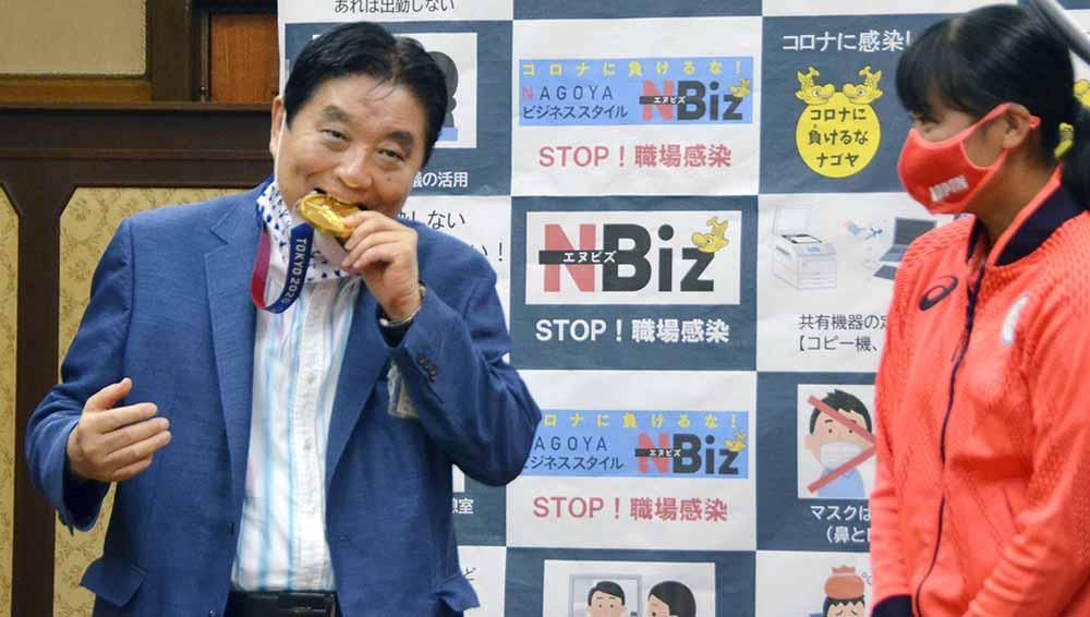 Wali Kota Nagoya Takashi Kawamura menggigit medali emas Olimpiade Tokyo 2020. - INDOSPORT