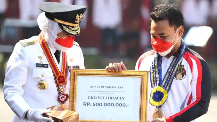 Gubernur Jawa Timur Khofifah Indar Parawansa memberikan lencana Jer Basuki Mawa Beya ke Eko Yuli Irawan di Gedung Negara Grahadi. Selasa (17/08/21). - INDOSPORT