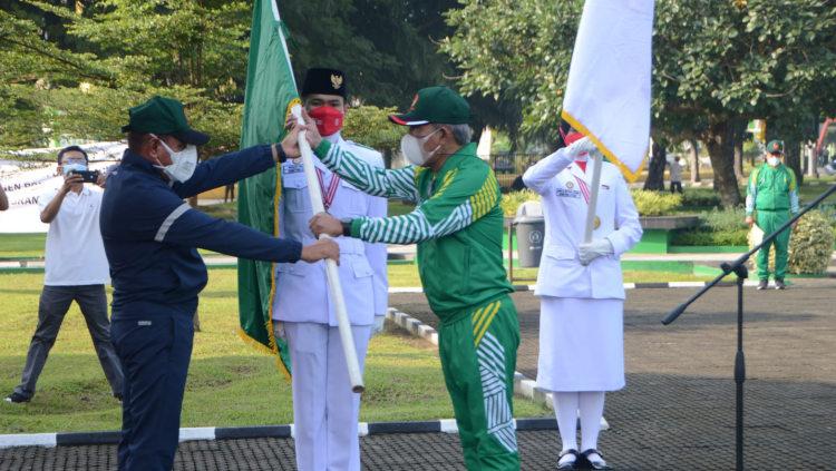 Gubernur Sumut, Edy Rahmayadi (kiri), menyerahkan bendera pataka kepada Ketua kontingen yang juga Ketua KONI Sumut, John Ismadi Lubis (kanan). - INDOSPORT
