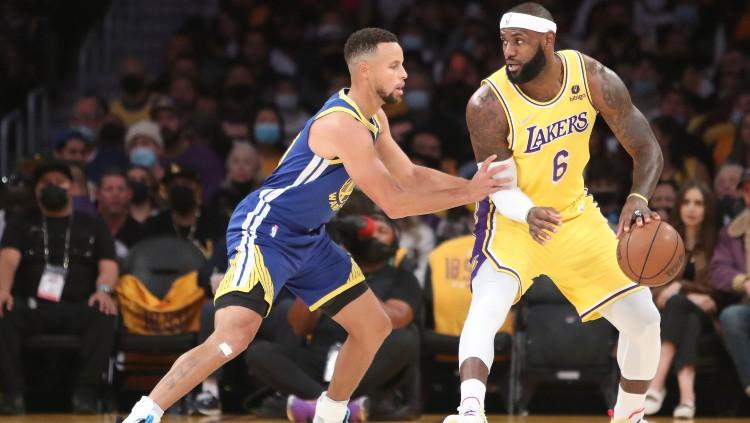 Stephen Curry (Warriors) mencoba merebut bola dari LeBron James (Lakers) di laga kedua NBA (20/10/21).