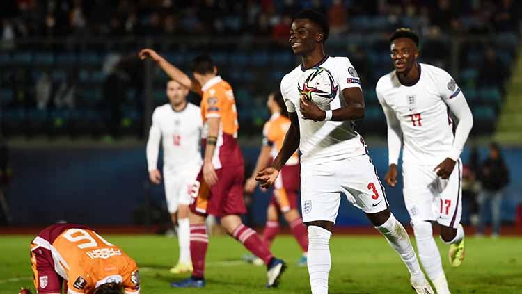 Bukayo Saka melakukan selebrasi sambil membawa bola.
