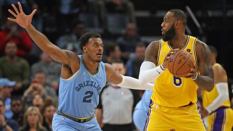 LeBron James (kanan) mencoba melewati Xavier Tillman Sr di laga Memphis Grizzlies vs Los Angeles Lakers (10/12/21).