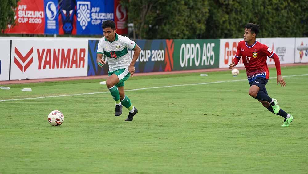 Bek kanan Timnas Indonesia, Asnawi Mangkualam (kiri) berusaha melewati penjagaan pemain Laos pada laga kedua fase grup B Piala AFF di Bishan Stadium, Minggu (12/12/21).