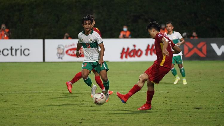 Pemain Vietnam tengah mengeksekusi bola, Pratama Arhan berusaha menggagalkan aksinya bersama Timnas Indonesia di Piala AFF 2020.