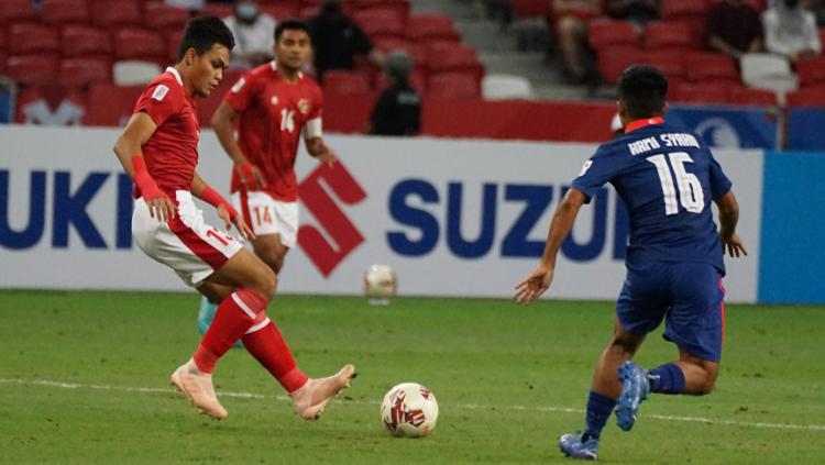 Fachrudin Aryanto mencoba untuk menghentikan bola dan berusaha melewati pemain Singapura.