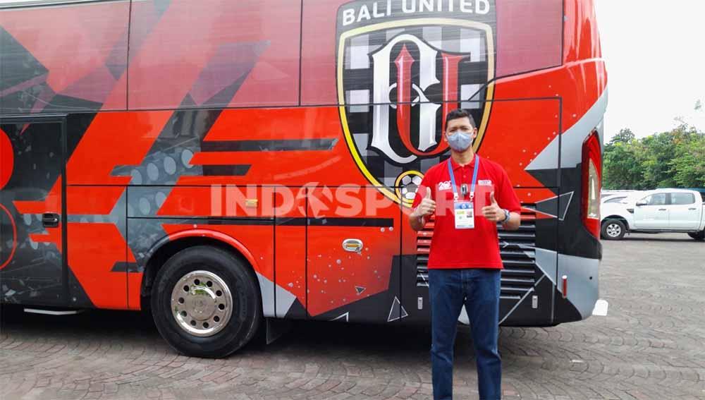 Legenda basket Tanah Air, Cokorda Raka Satrya Wibawa berpose dengan latar bus tim Bali United. Foto: Nofik Lukman Hakim/Indosport.com