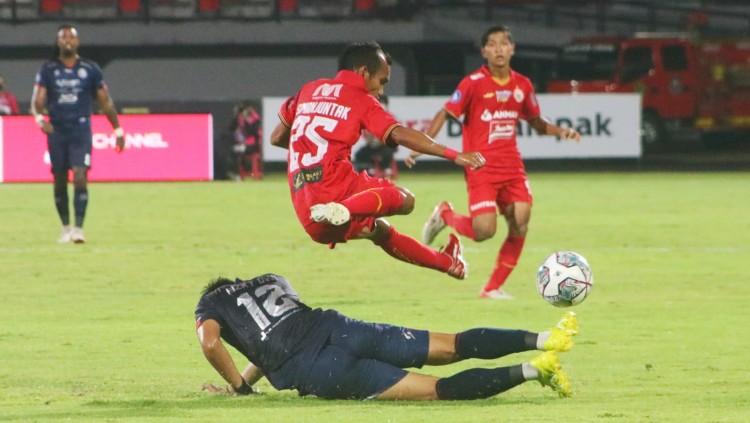 Winger Persija Jakarta, Riko Simanjuntak saat menghindari tackling bek Arema FC, Rizki Dwi Febrianto dalam lanjutan BRI Liga 1 2021/2022 di Stadion Kapten I Wayan Dipta, Gianyar, Sabtu (05/02/22). - INDOSPORT