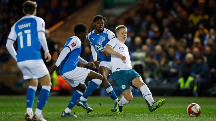 Oleksandr Zinchenko (kanan) melepaskan operan di tengah kawalan pemain Peterborough (02/03/22). (Foto: Reuters/John Sibley)