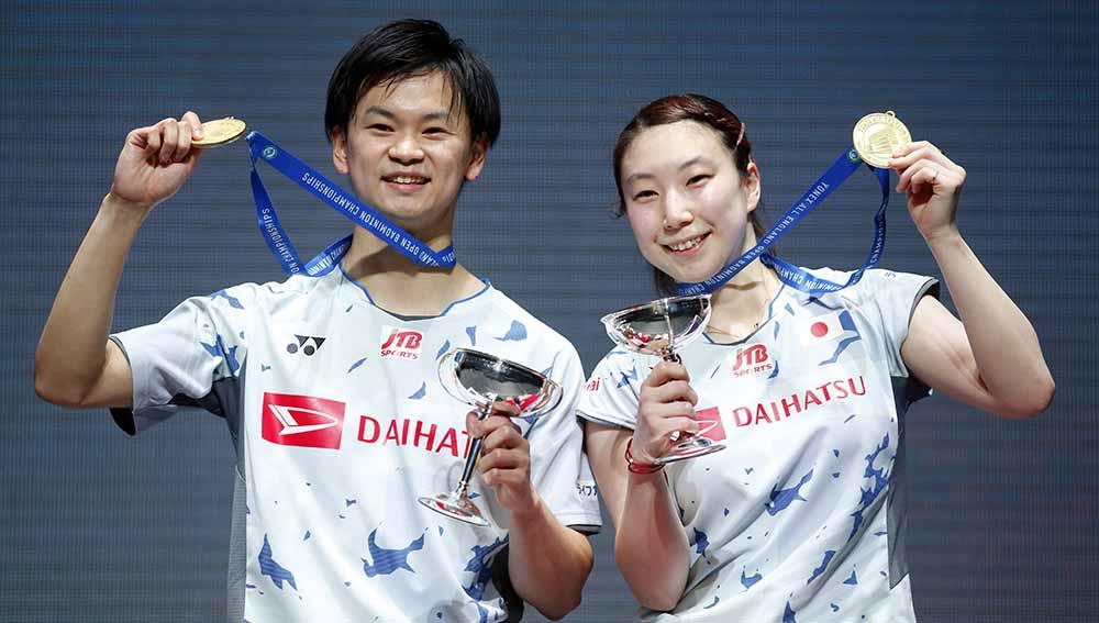 Ganda campuran asal Jepang, Arisa Higashino dan Yuta Watanabe merayakan dengan piala dan medali usai memenangkan final ganda campuran di All England Open 2022. Foto: Reuters/Ed Sykes