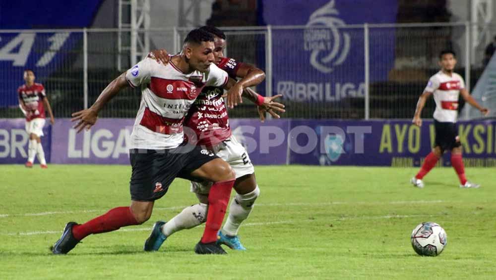 Perebutan bola gelandang Bali United, Eber Bessa (kanan) dengan bek Madura United, Jaimerson Xavier. Foto: Nofik Lukman Hakim/Indosport.com
