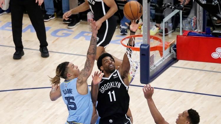 Kyrie Irving (tengah) mencoba menjaringkan bola di tengah hadangan lawan di laga Memphis Grizzlies vs Brooklyn Nets (24/03/22). (Foto: Reuters/Petre Thomas-USA TODAY Sports) - INDOSPORT