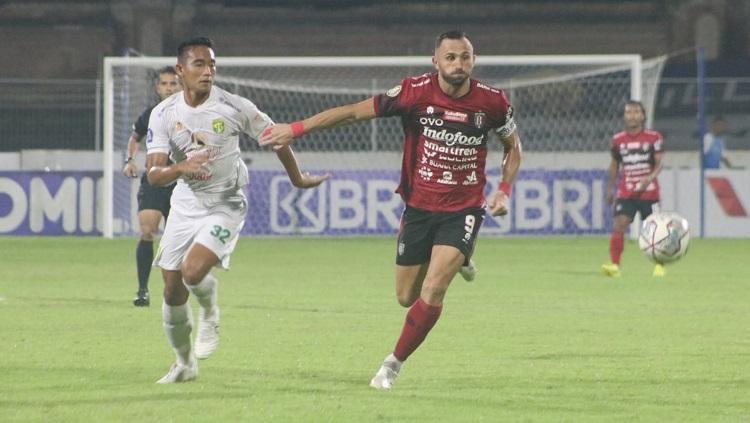 Penyerang Bali United, Ilija Spasojevic dikawal ketat bek Persebaya Surabaya, Rizky Ridho. Foto: Nofik Lukman Hakim/INDOSPORT - INDOSPORT