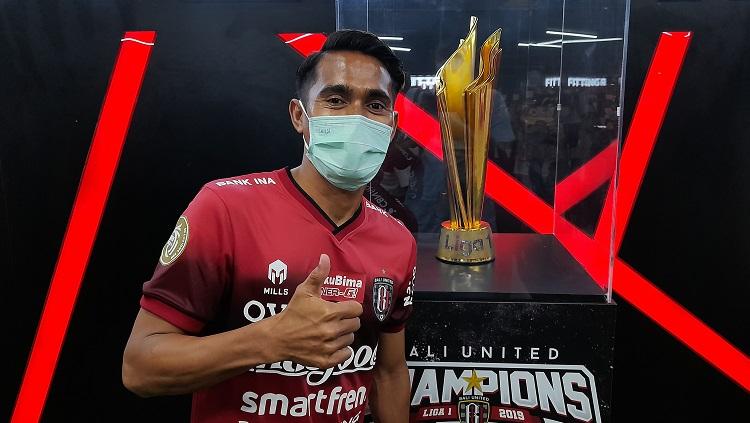 Muhammad Sidik Saimima saat berpose dengan replika piala juara Liga 1 di Bali United Megastore. Foto: Nofik Lukman Hakim/INDOSPORT