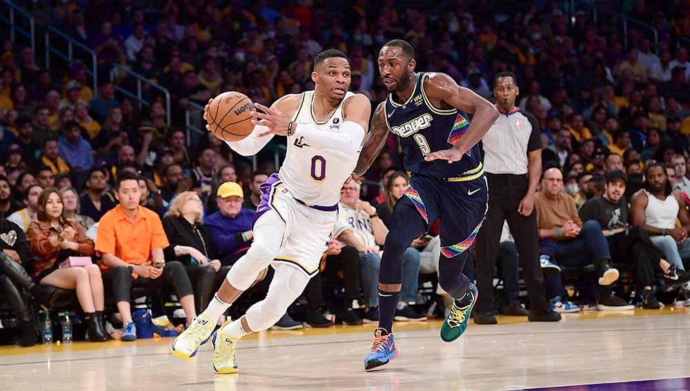 Pebasket Los Angeles, Lakers Russell Westbrook bergerak berusaha melewati pebasket Denver Nuggets. Davon Reed di laga MBA, Senin (04/04/22). Foto: Reuters/Gary A. Vasquez