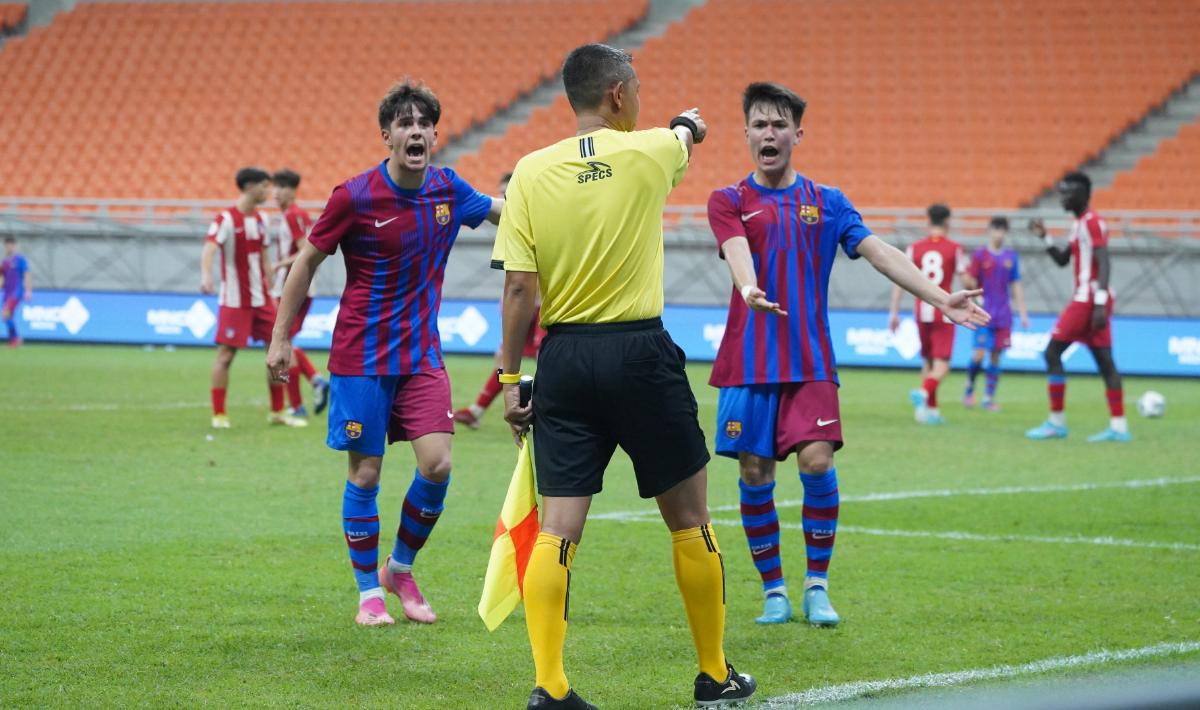 Protes dua pemain Barcelona U-18 kepada asisten wasit atas keputusan penalti yang diberikan kepada Atletico Madrid U-18 pada laga kedua turnamen International Youth Championship (IYC) 2022 di Stadion JIS, Jumat (15/04/22). Foto: Official Photo IYC 2022