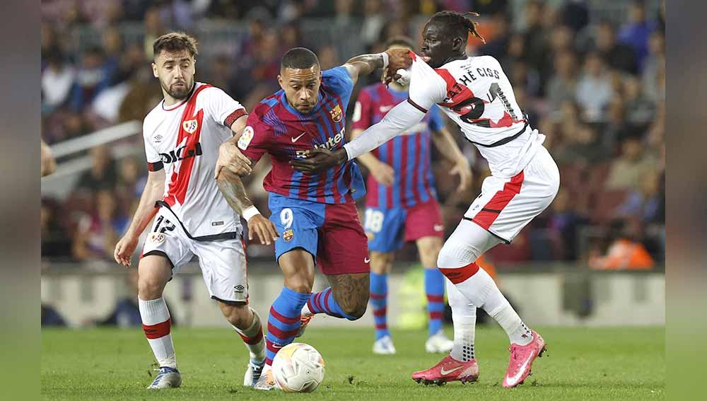Pemain Barcelona Memphis Depay di kawal ketat dua pemain Rayo Vallecano Pathe Ciss dan Unai Lopez. Foto: REUTERS/Albert Gea