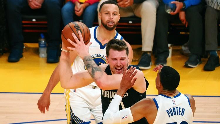 Luka Doncic (tengah) mencoba keluar dari hadangan Otto Porter Jr di laga Golden State Warriors vs Dallas Mavericks (21/05/22). (Foto: Reuters/Kelley L Cox-USA TODAY Sports)