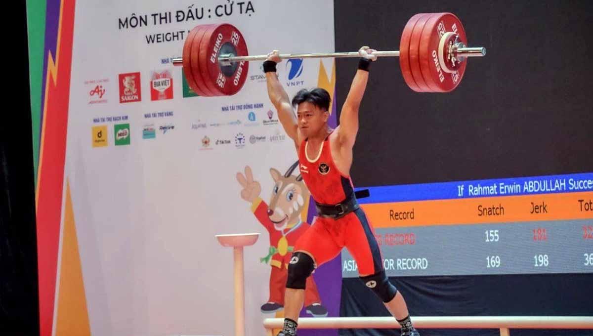 Rahmat Erwin Abdullah memamerkan medali emas yang didapatkannya di kelas 73kg putra di SEA Games 2021 Vietnam, Sabtu (21/05). Foto: NOC INDONESIA/MP MEDIA/EVAN ANDRAWS - INDOSPORT