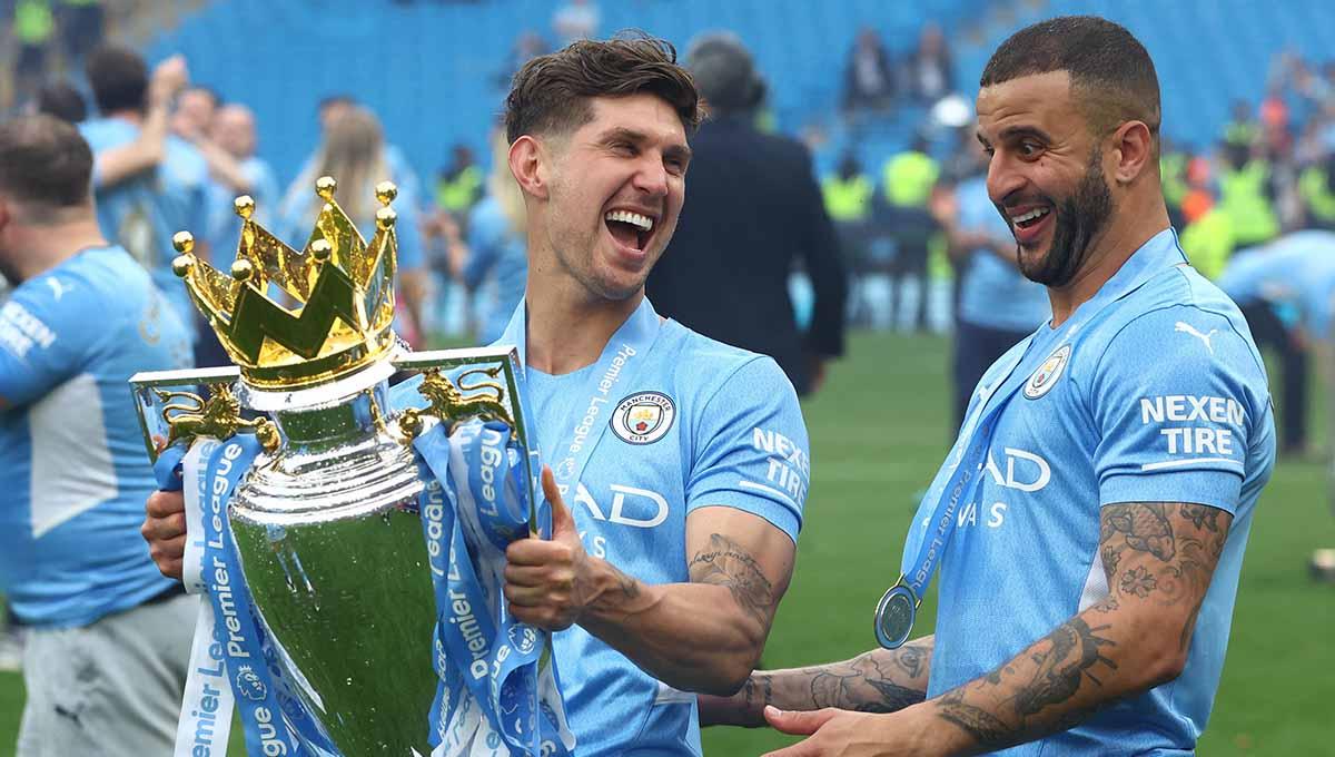 Pemain Manchester City John Stones dan Kyle Walker merayakan dengan trofi setelah juara Liga Inggris 2021/2022. Foto: REUTERS/Hannah Mckay