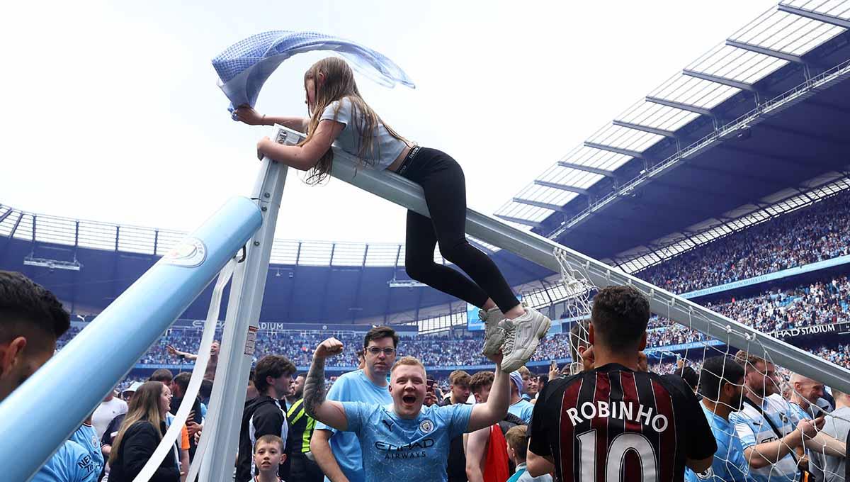 Seorang fans Manchester City memanjat tiang gawang saat mereka merayakan timnya menjuarai Liga Inggris 2021/2022. Foto: REUTERS/Hannah Mckay