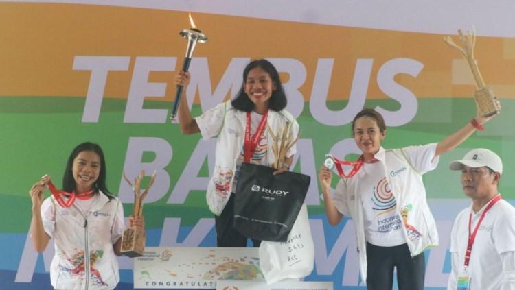 Odekta Naibaho mengangkat piala juara Indonesia International Marathon 2022 bersama Irma Handayani (kanan) dan Pretty Sihite (kiri). Foto: Nofik Lukman Hakim/INDOSPORT. - INDOSPORT