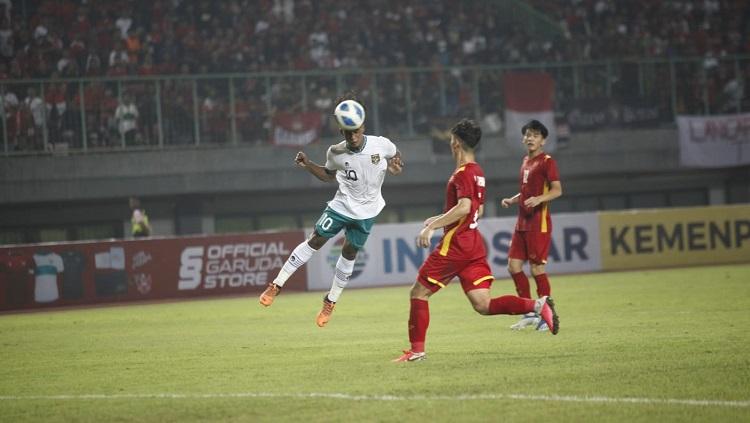 Pemain Timnas Indonesia U-19, Ronaldo Kwateh, tengah menyundul bola dibayang-bayangi pemain Vietnam di Piala AFF U-19. - INDOSPORT