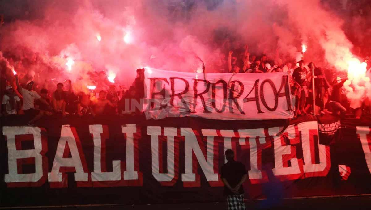 Suporter Bali United di tribun utara menyalakan flare dan membentangkan spanduk 