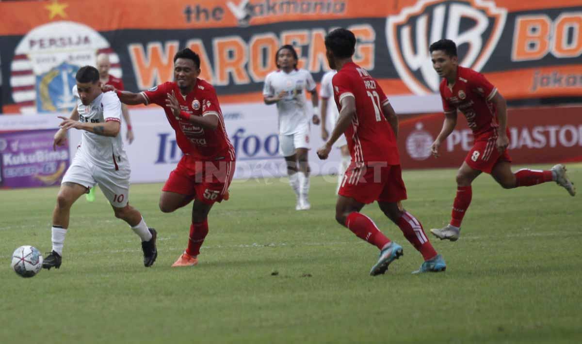 Bek Persija Jakarta, Maman Abdurrahman mencoba menghentikan pergerakan gelandang Persis Solo, Alexis Nahuel Messidoro pada laga Liga 1 di Stadion Patriot Candrabhaga, Minggu (31/07/22).