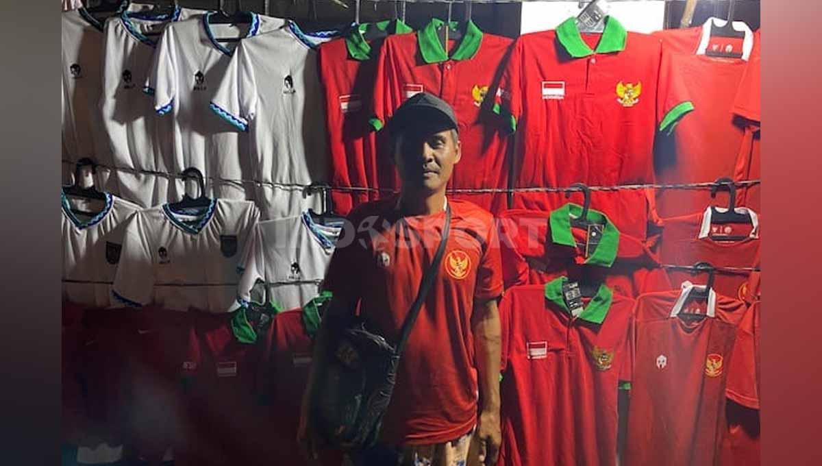 Kang Oman, pedagang jersey Timnas Indonesia asal Bandung di Piala AFF U-16 2022. Foto: Triyoga Sandi Pamungkas/INDOSPORT