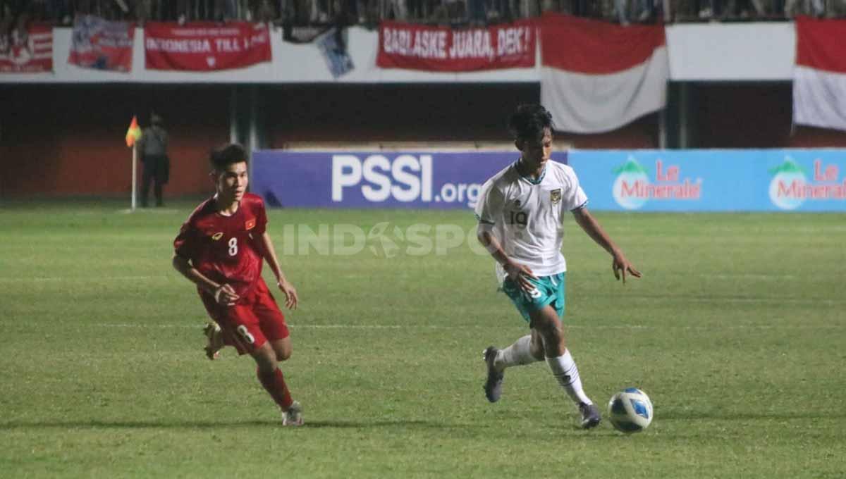 Indosport - Gelandang, Achmad Zidan Rossi saat menguasai bola dengan kawalan pemain Vietnam, Le Duc Phat. Foto: Nofik Lukman Hakim/INDOSPORT