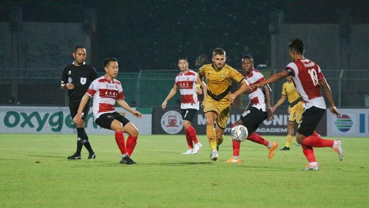 Gelandang Madura United, Lee Yu-jun, berduel di lini tengah.