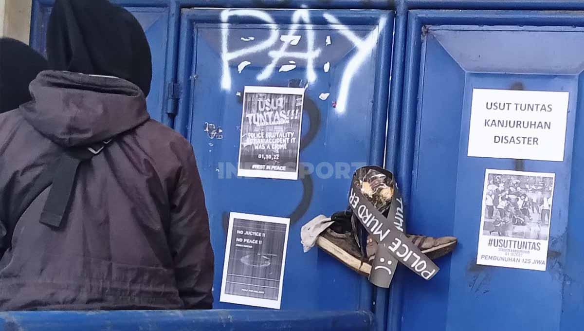 Pengunjung sedang melihat sepatu dan poster di Stadion Kanjuruhan.