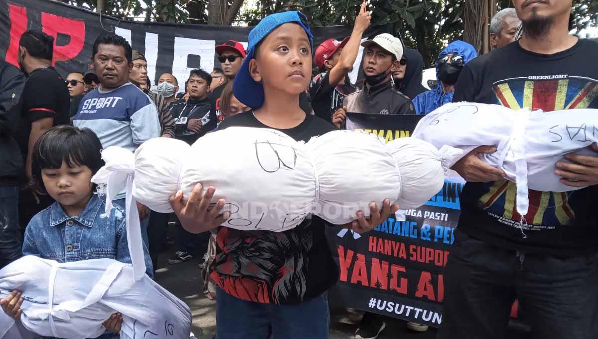 Aremania Licek (kecil) menggendong pocong tanda jatuhnya korban. (Foto: Ian Setiawan/INDOSPORT)