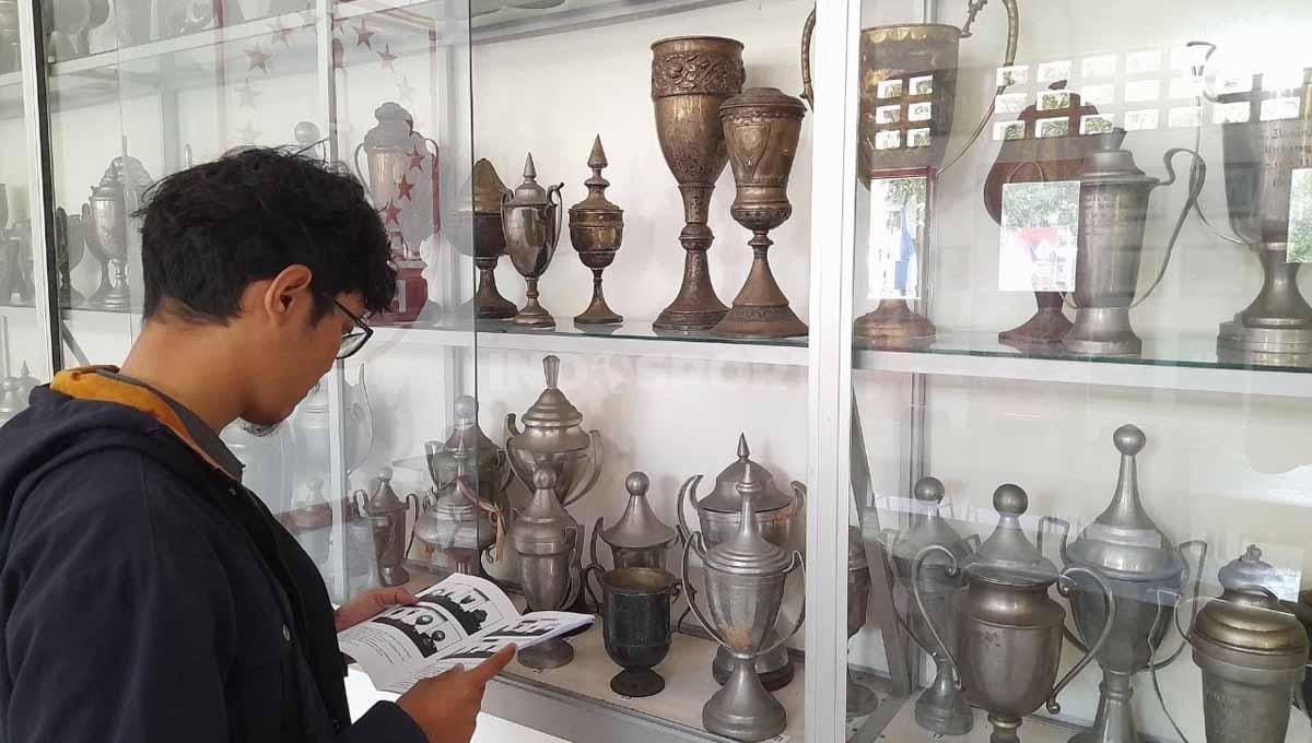 Pengunjung saat melihat keterangan setiap piala milik Persis Solo di Balai Persis. (Foto: Nofik Lukman Hakim/INDOSPORT) - INDOSPORT